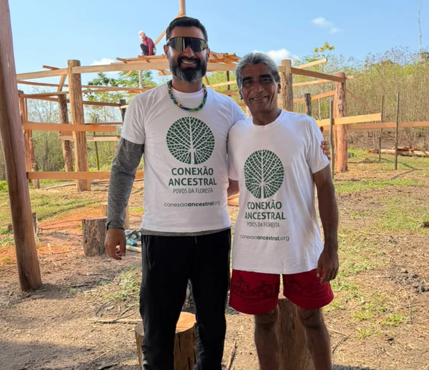 Homem indígena com uma criança e outro integrante da comunidade